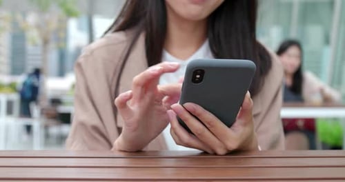 Frau benutzt Handy im Outdoor-Café