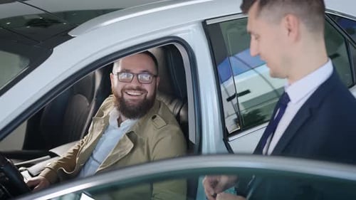 an Adult Man Sits in the Salon of a New Car in a Dealership