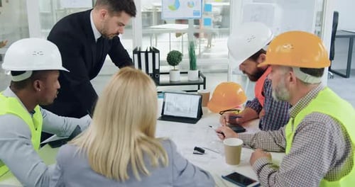 Construction Team Reviews Plans in Bright Office