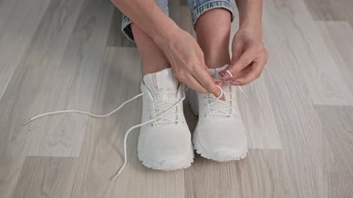 Lifestyle Young Woman Tied the Laces on Comfortable Sports Shoes While Sitting on Floor in Room for