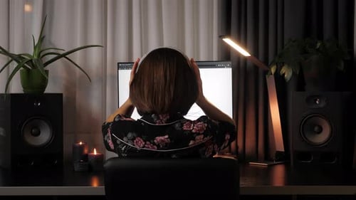 La directora de proyectos se pone los auriculares y trabaja en una computadora portátil en una ajetreada oficina creativa