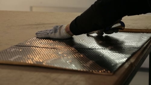 Craftsperson Cutting Silver Foil Material in Workshop