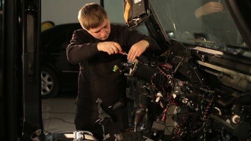 Man Repairing a Car's Electrical System with Screwdriver