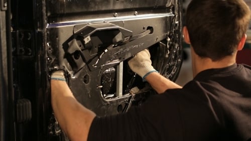Man Repairs Car Door Mechanism in Indoor Setting