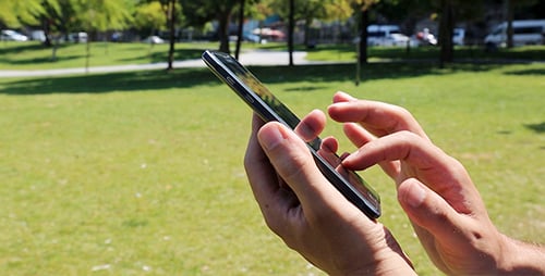Hand Using Touch Screen Phone in Park Setting