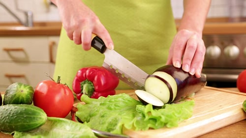 Woman Slicing Eggplant on Cutting Board in Kitchen