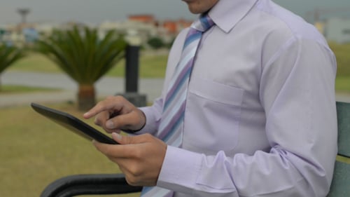 Mann auf Bank mit Tablet-PC