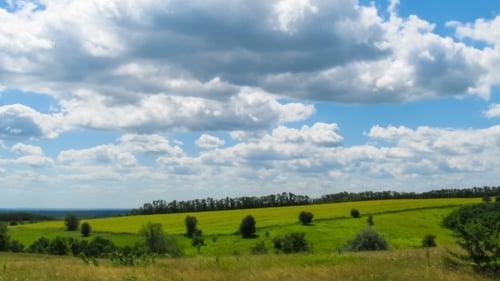 Paisaje, nubes moviéndose sobre un campo con árboles.