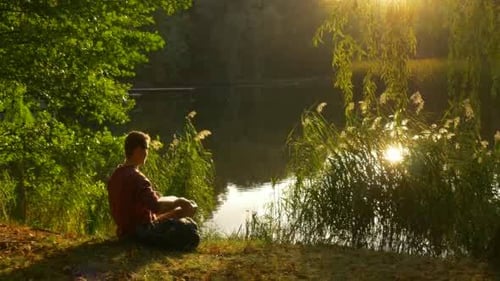 Man Working on Laptop by Scenic Lake at Sunset