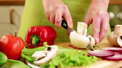 Woman Cutting Vegetables for Salad in Kitchen