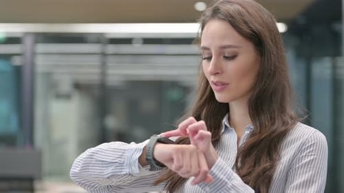 Smiling Woman Interacting with Smart Watch in Office