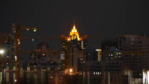Night View of City Skyline and Construction Cranes