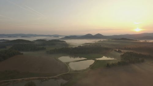 Misty Sunrise Over Rolling Green Hills