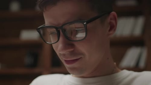 Close Up of Student in Eye Glasses with Reflection of Man Typing on Laptop