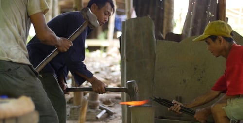 Blacksmiths Shape Hot Metal with Hammers Together
