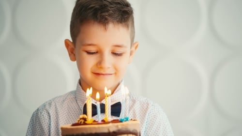 Boy with Brown Hair Blows Out Birthday Candles
