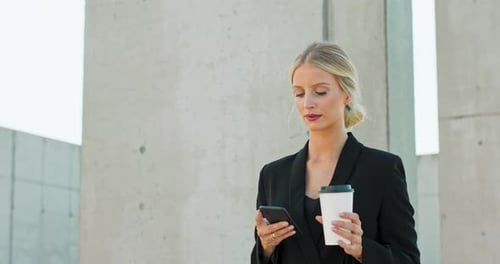 Woman Using Smartphone with Coffee Cup in Urban Setting