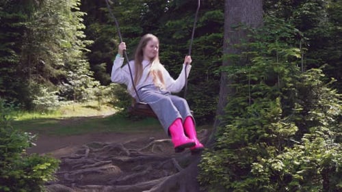 Chica en columpio en el bosque.