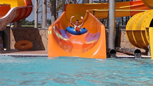 Girl Rides Water Slide on Tube at Water Park