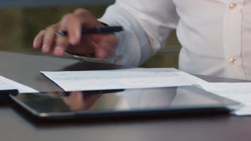 Man Signing Documents in Office with Tablet