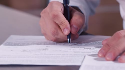 Person Completing Medical Form With Pen Close Up