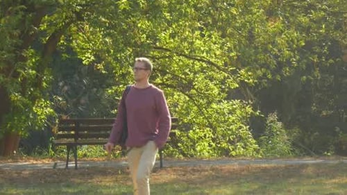 Man Walking Through Green Park on Sunny Day