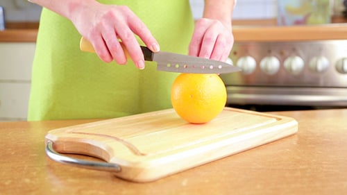 Frauenhände schneiden Orange