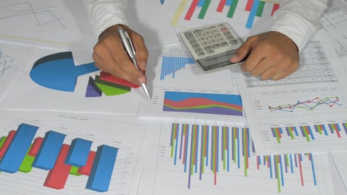 Hands Calculating Data with Charts and Calculator