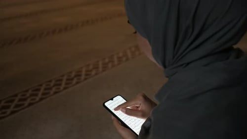 Junge Frau liest Koran-Smarthphone