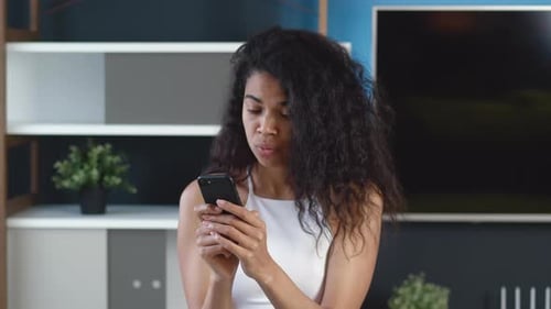 Surprised African American Young Woman Looking at Smartphone, Wonder and Saying Wow. Modern Office