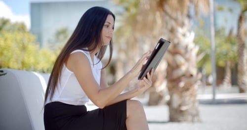Woman Using Tablet Outdoors on a Sunny Day