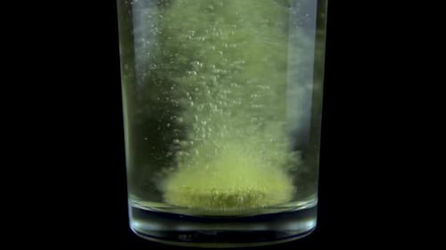 Green Tablet Dissolving in Glass of Water