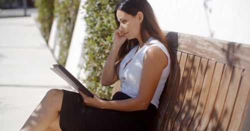 Woman Using Tablet and Phone on Bench