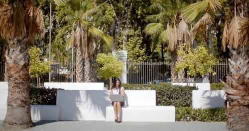 Young Woman Works on Laptop Outdoors in the City