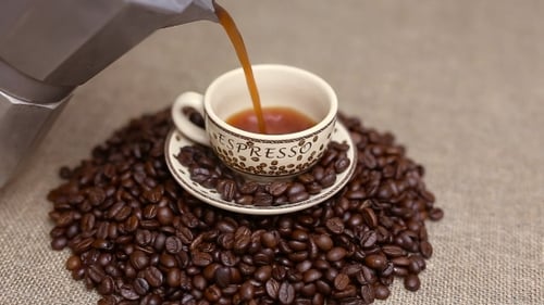 Eine Tasse Kaffee mit Kaffeebohnen gießen