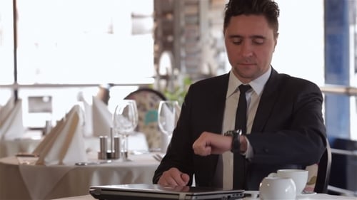 Professional Man Waits at Restaurant with Laptop and Tea