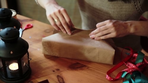 Woman Wrapping Holiday Gift with Brown Paper