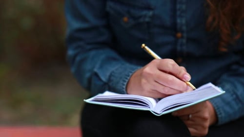 Young Woman Journaling Outside on a Sunny Day