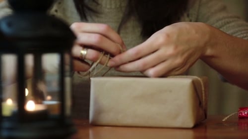 Woman Wrapping Christmas Gift with Twine