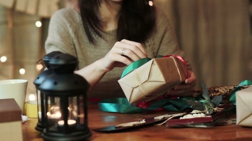 Woman Wrapping Christmas Gifts with Ribbons and Decor