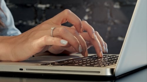 Woman Typing on Laptop Keyboard in Office