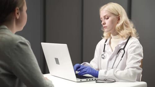 Female Doctor Talking with Patient During Visit at Doctors Office