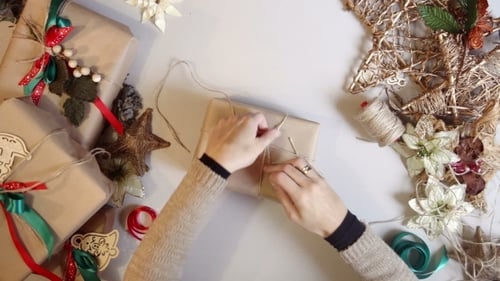 Creative Hands Wrapping Christmas Gift with Twine and Ribbon