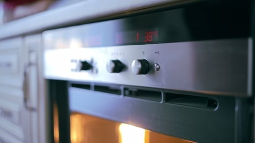 Hand Adjusting Oven Temperature in Modern Kitchen