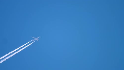 Airplane Flying Through Blue Sky with Contrails