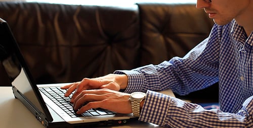 Man Typing on Laptop Indoors