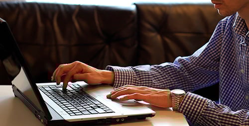 Young Adult Typing on a Laptop at Home