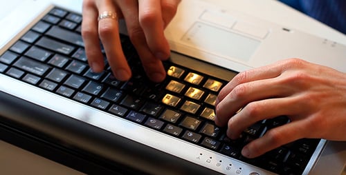 Hands Typing on Laptop Keyboard in Workplace