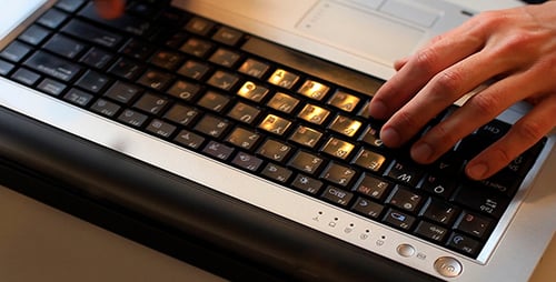 Fingers Typing on Illuminated Laptop Keyboard