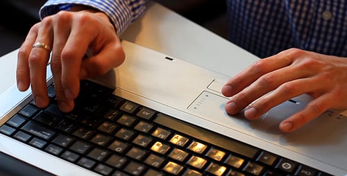 Adult Typing on Laptop in Bright Office